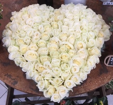Composition piquée en forme de cœur composée de roses blanches